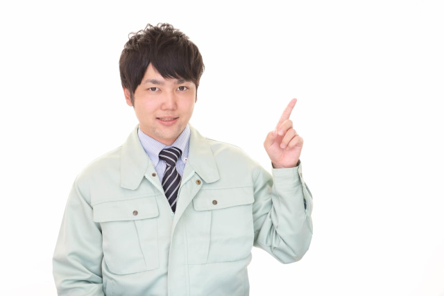 指差しする作業服の男性