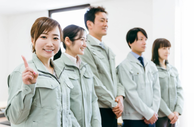 指差しする作業服の女性
